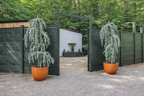 A gated entrance with a gravel path leading to a building with a white exterior and a wooden fence.