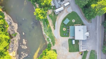An aerial view of a property with a river, green areas, and a building with a flat roof.