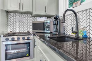 A kitchen with a stove, oven, microwave, and a sink with a faucet.