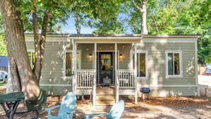 A small, single-story house with a porch, a front door, and a small table and chairs outside.