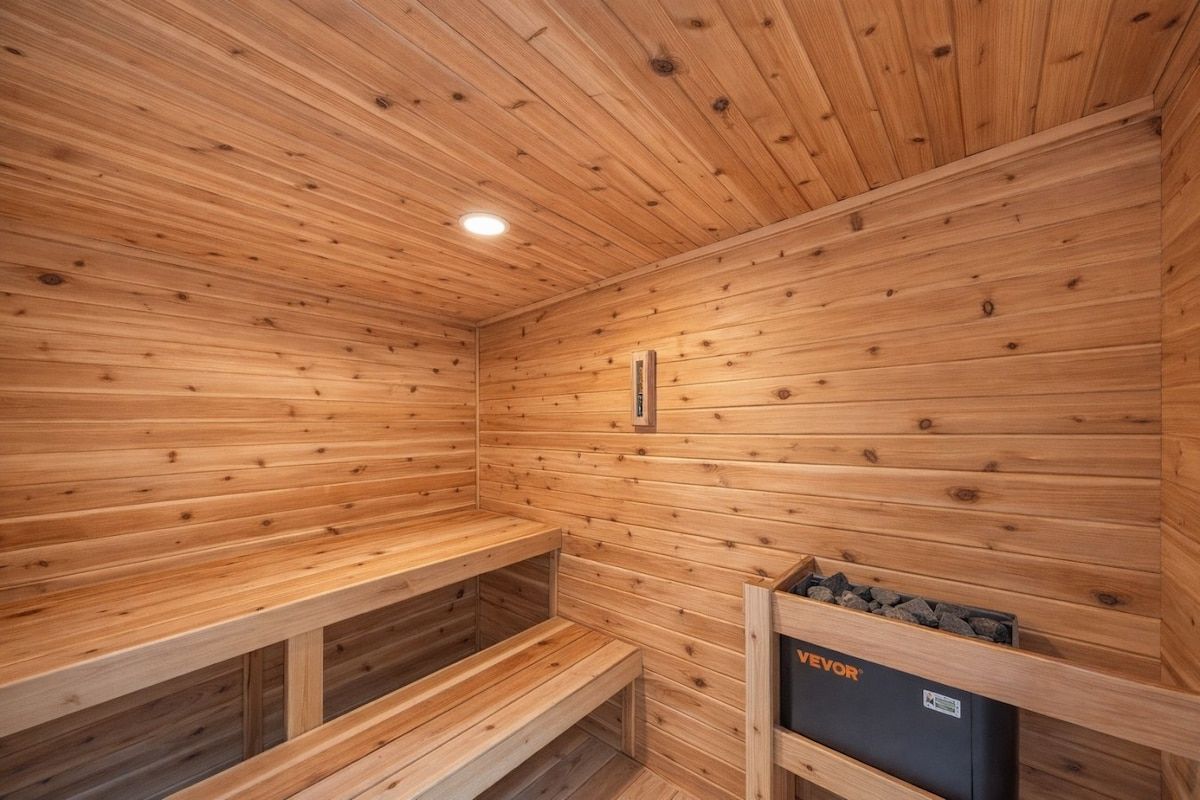 A wooden sauna with benches and a control panel.