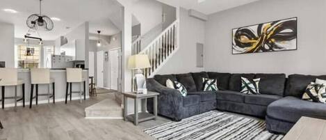 A modern living room with a gray sectional sofa, a coffee table, and a patterned rug.