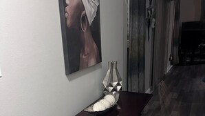 A hallway with a dark wooden table, a decorative vase, and a framed artwork on the wall.