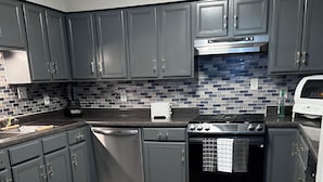 A modern kitchen with grey cabinets, a stainless steel range, and a tiled backsplash.