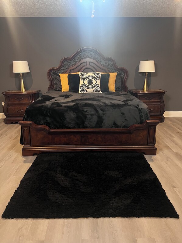 A bedroom with a dark wood bed, two nightstands, a black rug, and a chandelier. - Charming house perfectly located in Central City near most popular venues. (New Orleans)