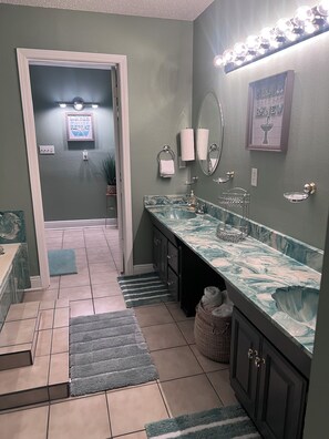 A bathroom with a marble sink, a mirror, and a towel rack. There is a door leading to another room. - Charming house perfectly located in Central City near most popular venues. (New Orleans)