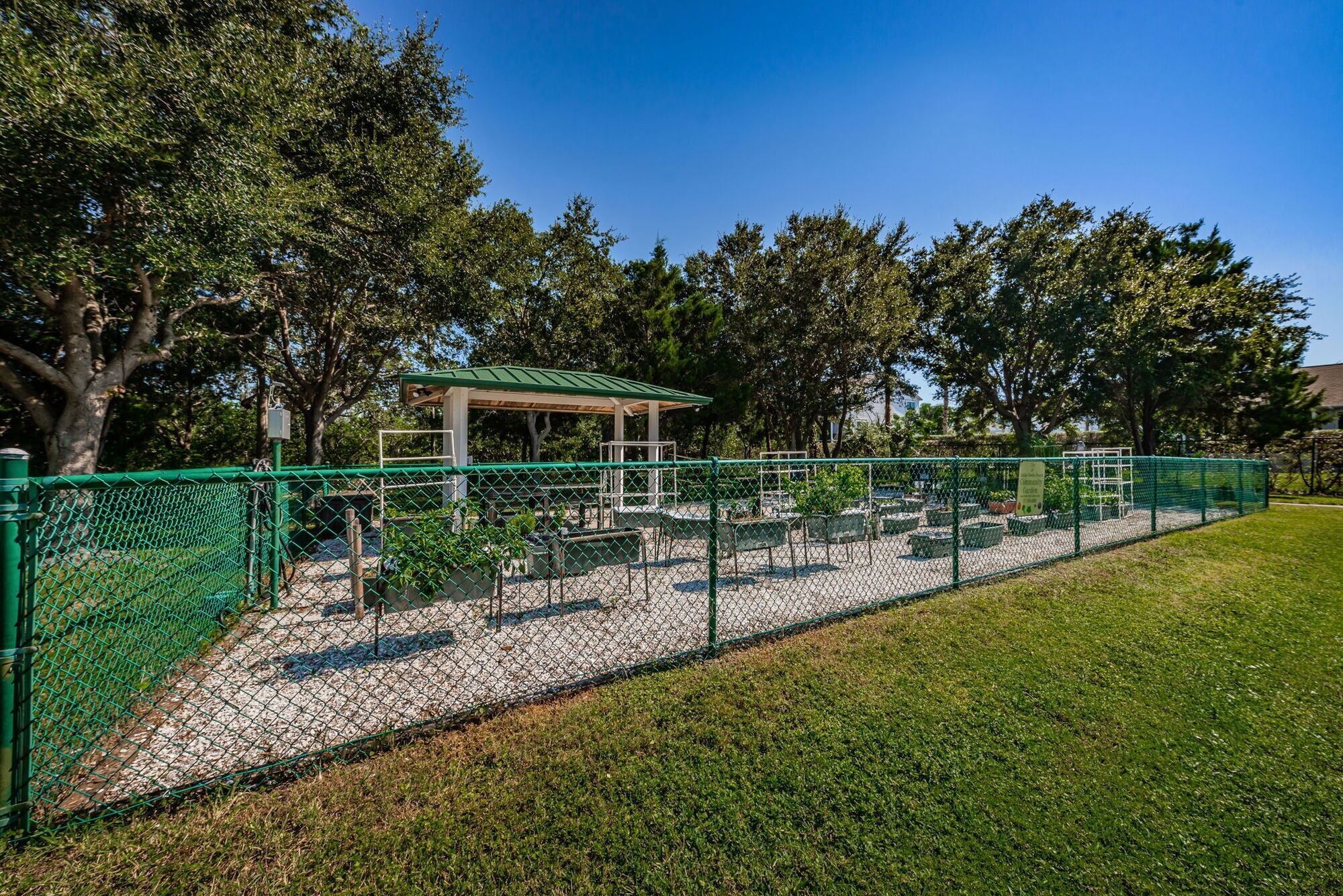 A fenced outdoor area with a gazebo, benches, and planters.