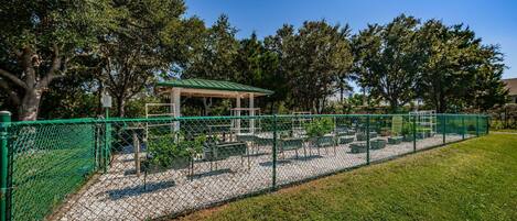 A fenced outdoor area with a gazebo, benches, and planters.