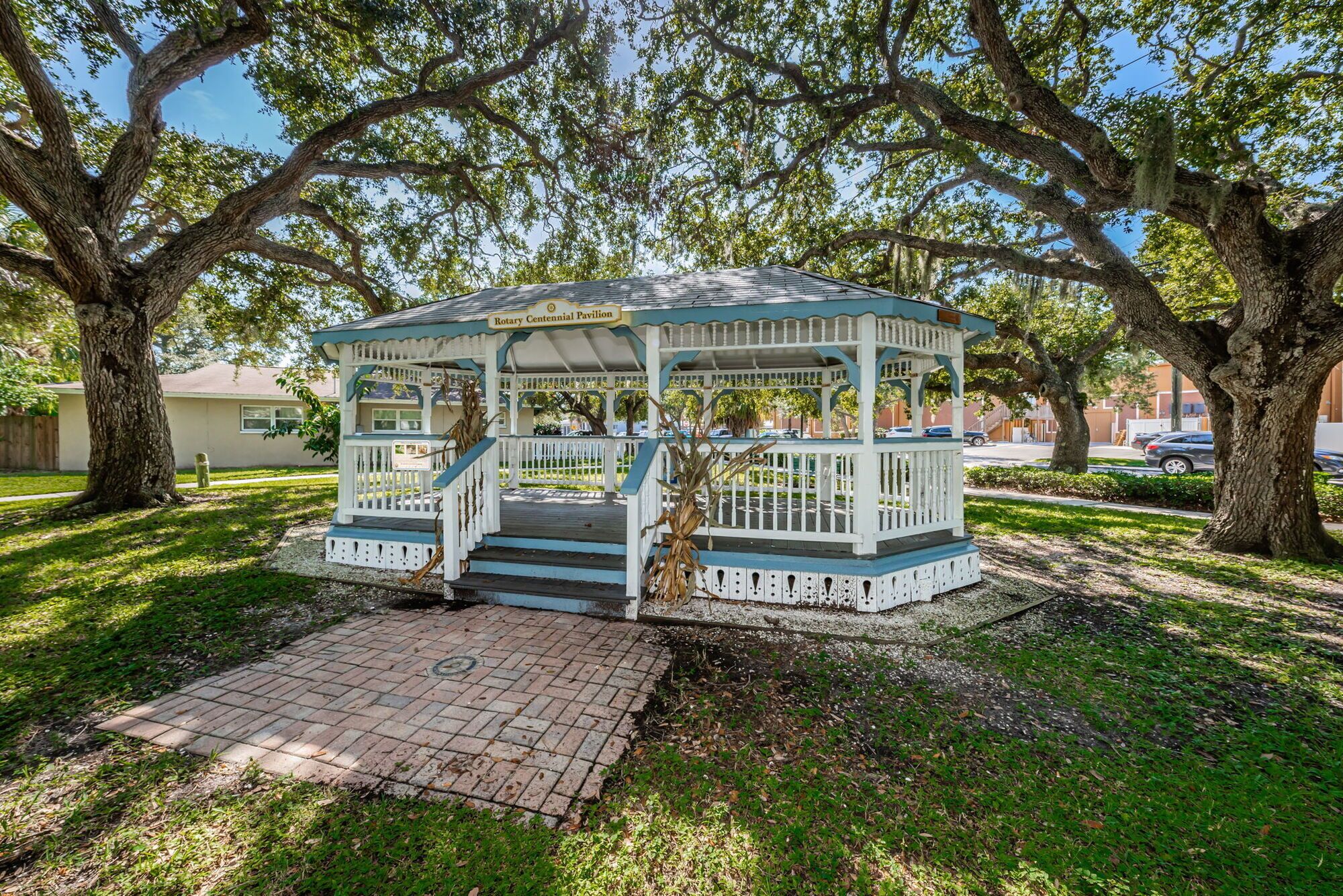 A gazebo with a blue and white color scheme, a covered entrance, and a brick pathway leading to it.