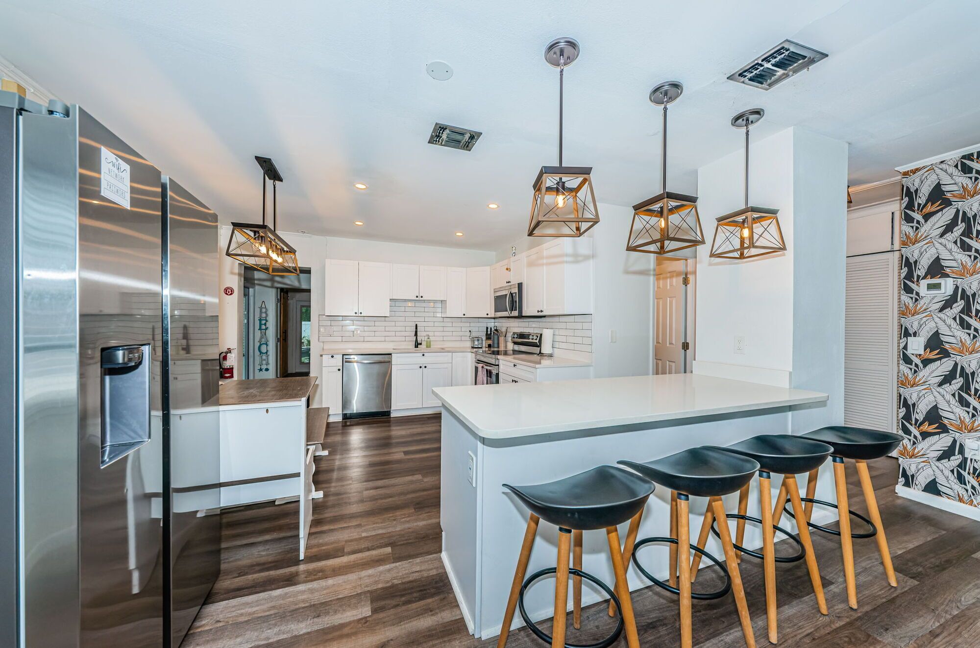 A modern kitchen with white cabinets, stainless steel appliances, and a central island with bar stools.