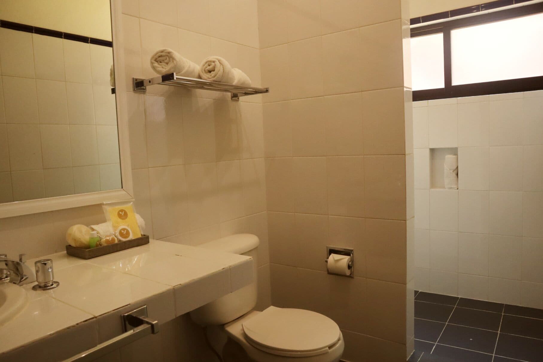 Un baño con inodoro, lavamanos y perchero para toallas.