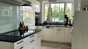 Een moderne keuken met witte kasten, een zwart aanrecht en een groot raam dat voor natuurlijk licht zorgt.