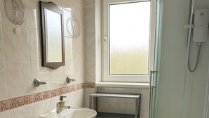 Un baño con inodoro, lavamanos y cabina de ducha de vidrio.