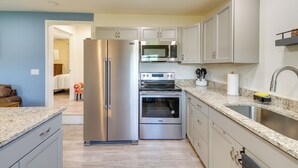 A modern kitchen with stainless steel appliances, light-colored cabinets, and a granite countertop. - 'The Garden Cottage' w/ Yard & Views in Erwin! (Erwin)