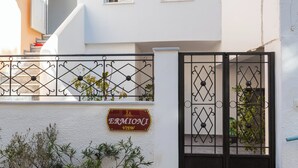 Um edifício branco com um portão preto, plantas em vasos e uma placa que diz 'ERMIONI View'.