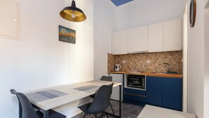 Uma cozinha compacta com área de refeições, com design moderno e uma parede de proteção decorativa, chaleira e cafeteira.