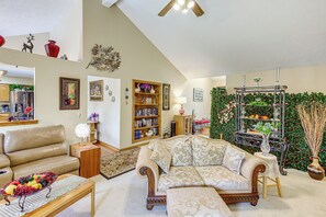 A living room with a sofa, a coffee table, a bookshelf, and a decorative wall.