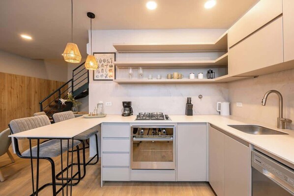 A modern kitchen with a central island, built-in oven, and stainless steel appliances.