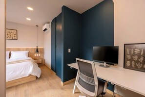 Une chambre d’hôtel moderne équipée d’un lit, d’un bureau, d’une chaise et d’une reproduction botanique encadrée accrochée au mur.