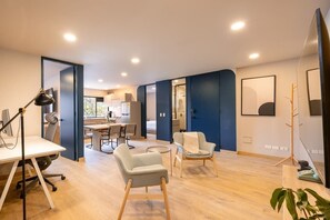 Un espacio de sala y comedor moderno y de planta abierta, con un escritorio grande, asientos cómodos y vistas al exterior.