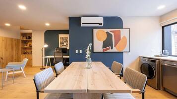Una sala de reuniones moderna con una larga mesa de madera, sillas cómodas, una pizarra y un equipo de aire acondicionado.