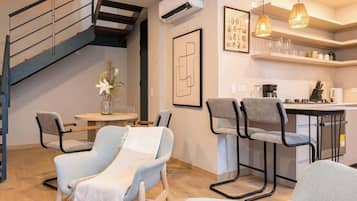Una cocina moderna con comedor, que incluye una escalera, sillas y una cafetera.