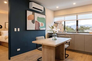 A modern kitchen with a dining area, featuring a wooden table, chairs, and a view of the outdoors.