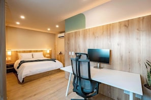 A modern hotel room with a wooden wall, a bed with white linens, a desk with a computer, and a TV. - Digital Nomad Paradise 2 units-3BR Oasis in Manila (Medellín)