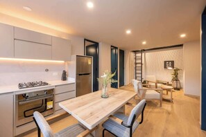 A modern kitchen with a wooden table and chairs, a refrigerator, and built-in cabinets.