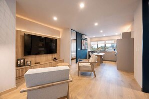 Een moderne woonkamer met een flatscreen televisie, een bank en een eethoek met een tafel en stoelen.