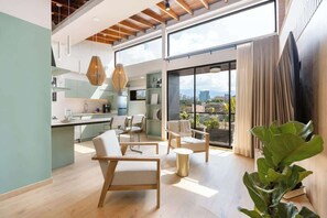 A spacious living area with a kitchen, large windows, and a balcony with plants.
