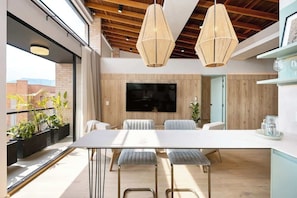 A modern dining area with a large table, cushioned chairs, and pendant lights.