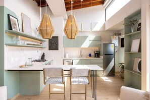 Une cuisine moderne dotée d’un îlot central, de luminaires suspendus et d’appareils électroménagers intégrés.