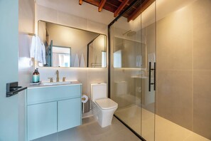 Een moderne badkamer met een douchecabine van glas, een wit toilet en een wastafel met spiegel.
