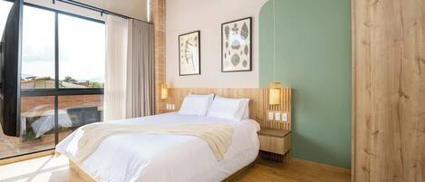 A modern bedroom with a large bed, wooden headboard, and a view through a sliding glass door.