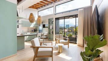 Amplia sala de estar con cocina, comedor y ventanas grandes que ofrecen vistas a la ciudad.
