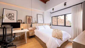 Un dormitorio moderno con cama, escritorio y ordenador.