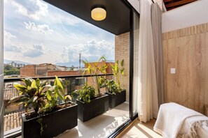 A balcony with potted plants, a view of the cityscape, and a wooden wall.