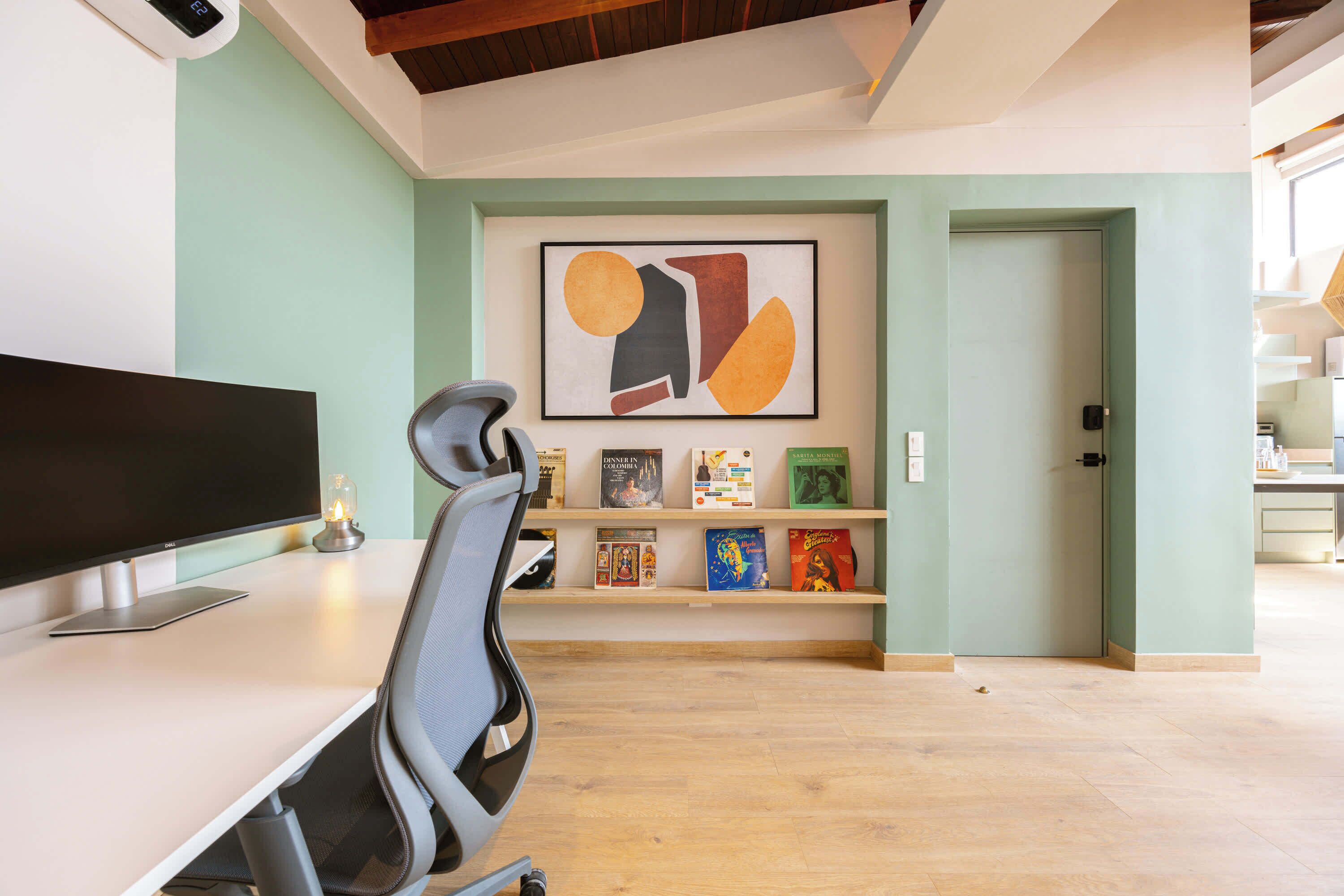 Un espacio de oficina moderno con un escritorio, una silla y una estantería con libros y objetos decorativos.