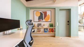 Un espacio de oficina moderno con un escritorio, una silla y una estantería con libros y objetos decorativos.