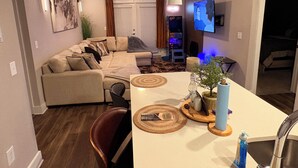 A modern living room with a sectional sofa, a dining area with a central island, a TV mounted on the wall, and a ceiling fan. -  Feel at home in our 2 Bed 2 Bathroom, pool view, game room,  palace in Atlanta. (Atlanta)