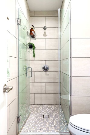 A glass-enclosed shower with a tiled floor, a toilet, and a hand dryer mounted on the wall. - Short North/Downtown | Steps to High St | Walk to Convention Ctr | Free Parking (Columbus)