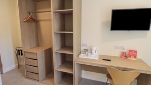 A room with a wooden wardrobe, a desk with a chair, a television, and a tray with a kettle and a mug. - Jubilee Single Bedroom Ground-floor (Penrith)