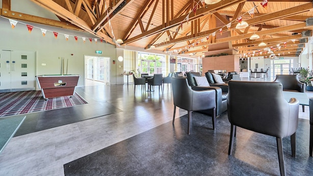 A spacious indoor area with high ceilings, wooden beams, and modern seating arrangements. - Jubilee Single Bedroom Ground-floor (Penrith)