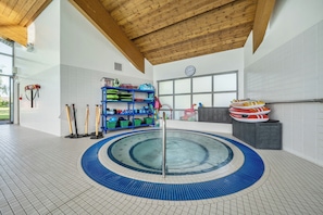 A swimming pool with a blue and white tiled floor, surrounded by a wooden ceiling and white walls. - Jubilee Single Bedroom Ground-floor (Penrith)