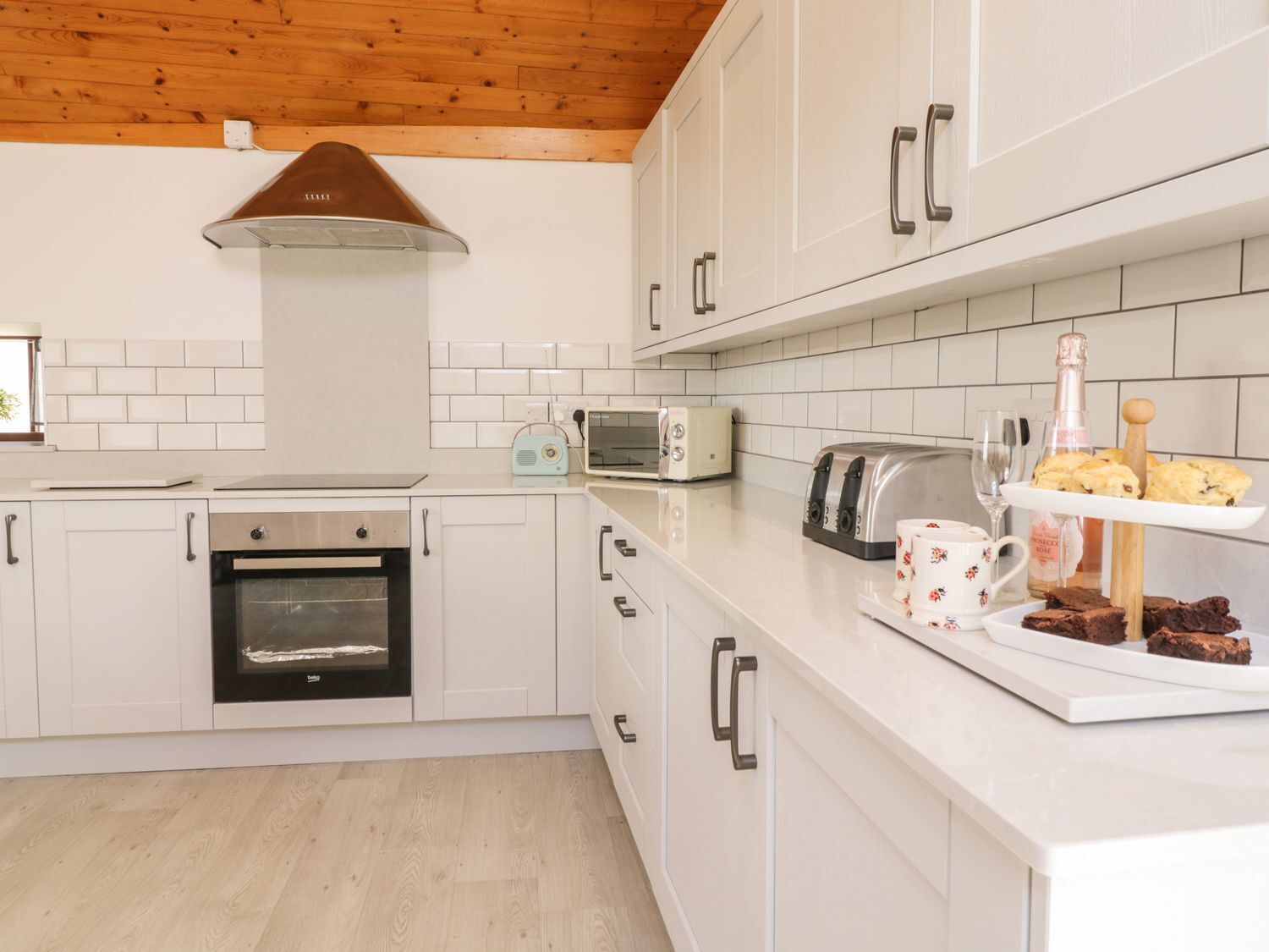 A modern kitchen with white cabinets, a built-in oven, a microwave, and a toaster.