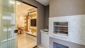 Una cocina moderna con una parrilla integrada, armarios blancos y un comedor con mesa y sillas.