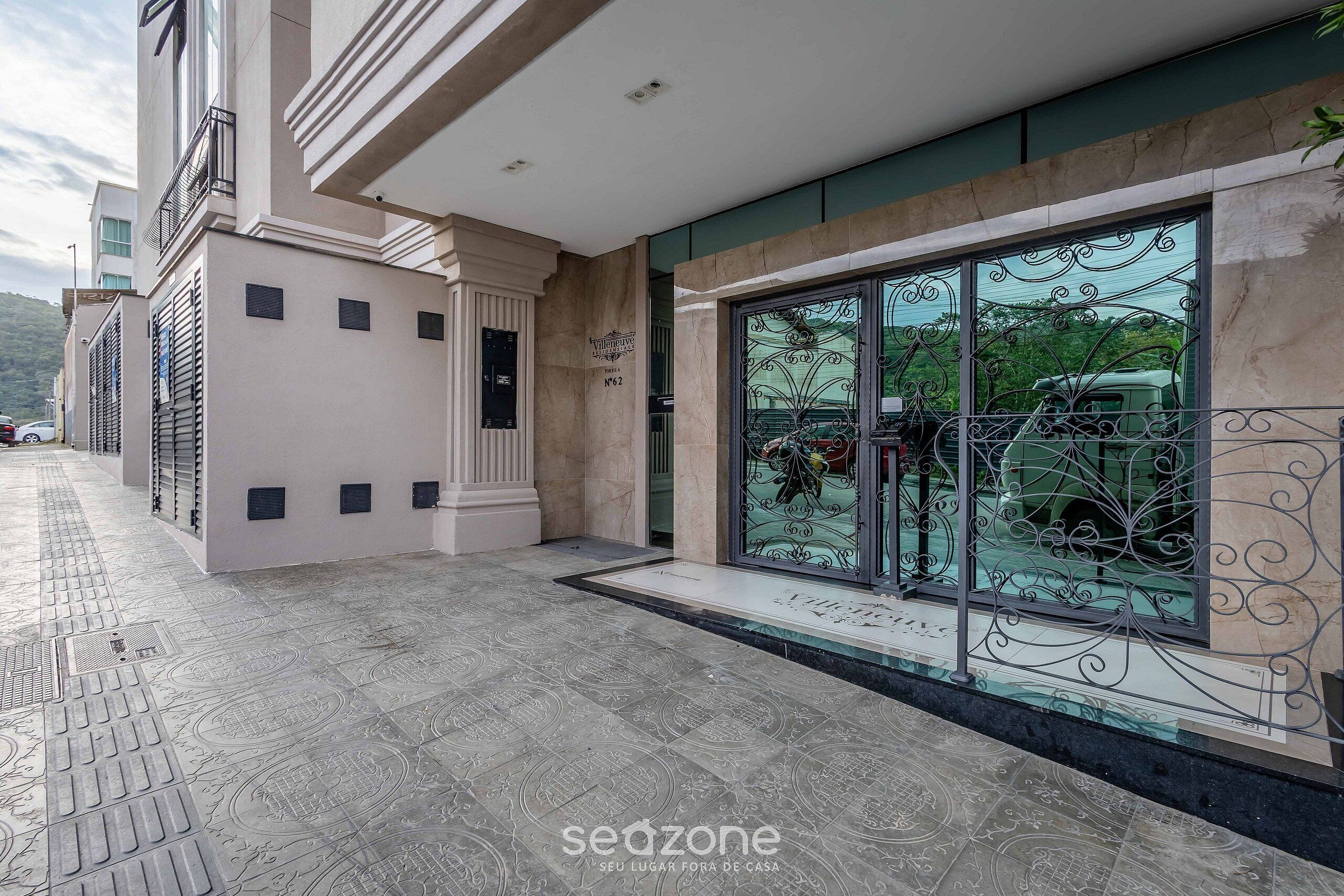 Un bâtiment moderne doté d’une grande entrée en verre, d’un sol carrelé et d’une rambarde en métal.