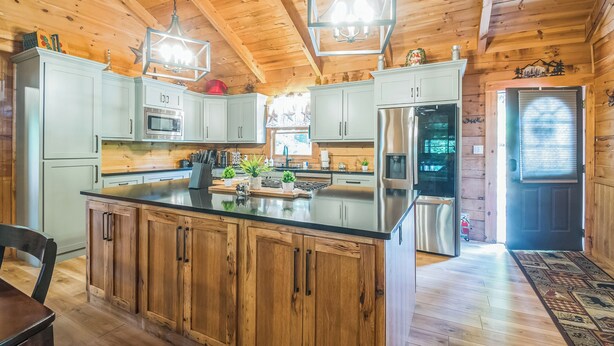 Une cuisine de style rustique, avec des éléments en bois, un grand îlot central, des appareils en acier inoxydable et des luminaires suspendus.