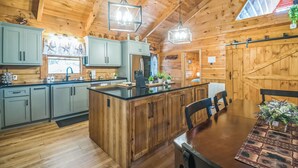 L’intérieur d’un chalet en bois comprend une cuisine avec des meubles de couleur bleu clair, un îlot central et des luminaires suspendus.